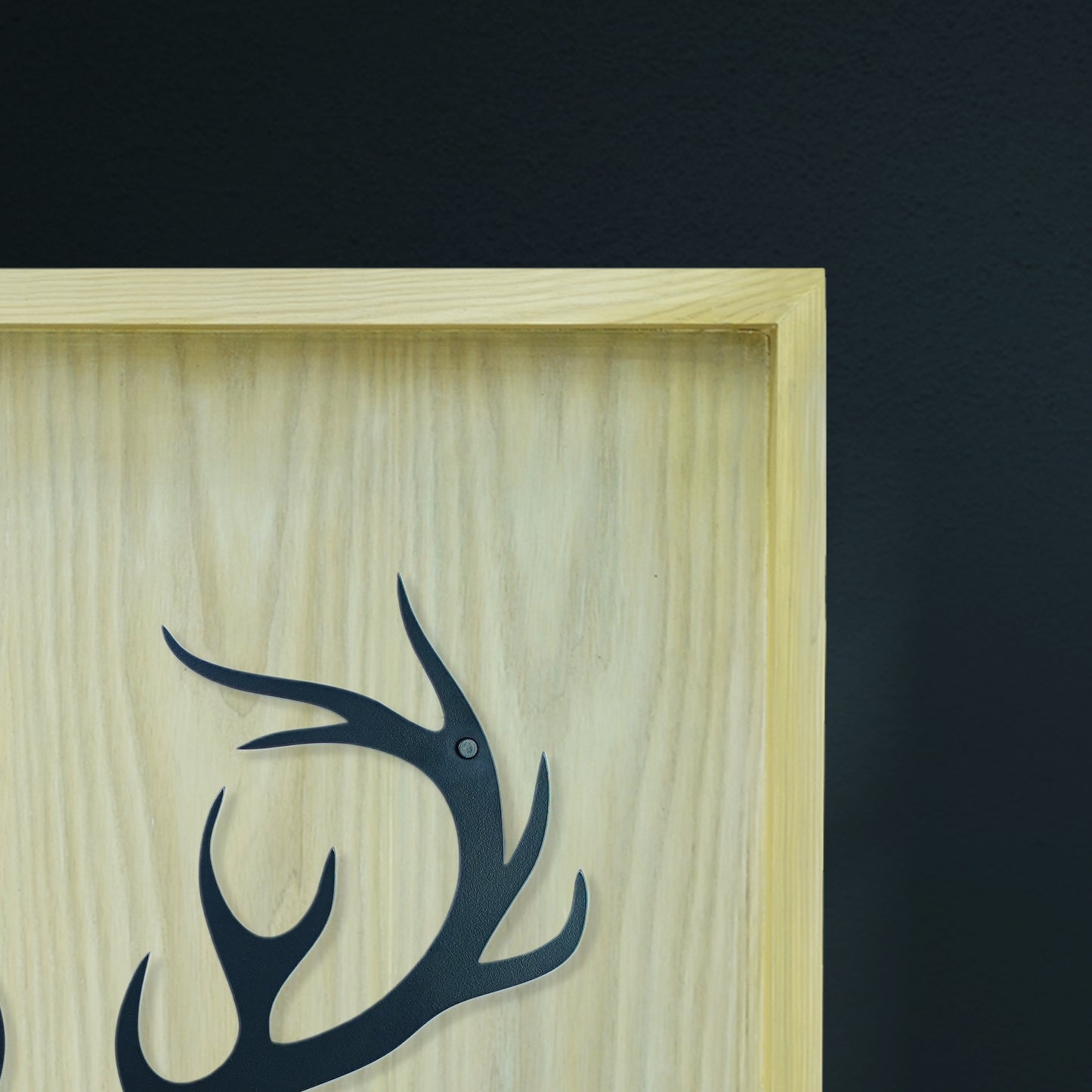 Wooden plaque with black deer antlers design on a dark background