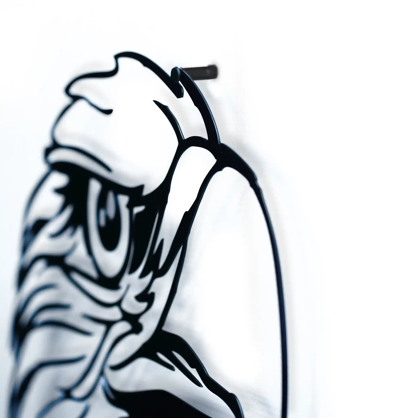 Black metal wall art of a stylized face of eagle on a white wall showing the shud