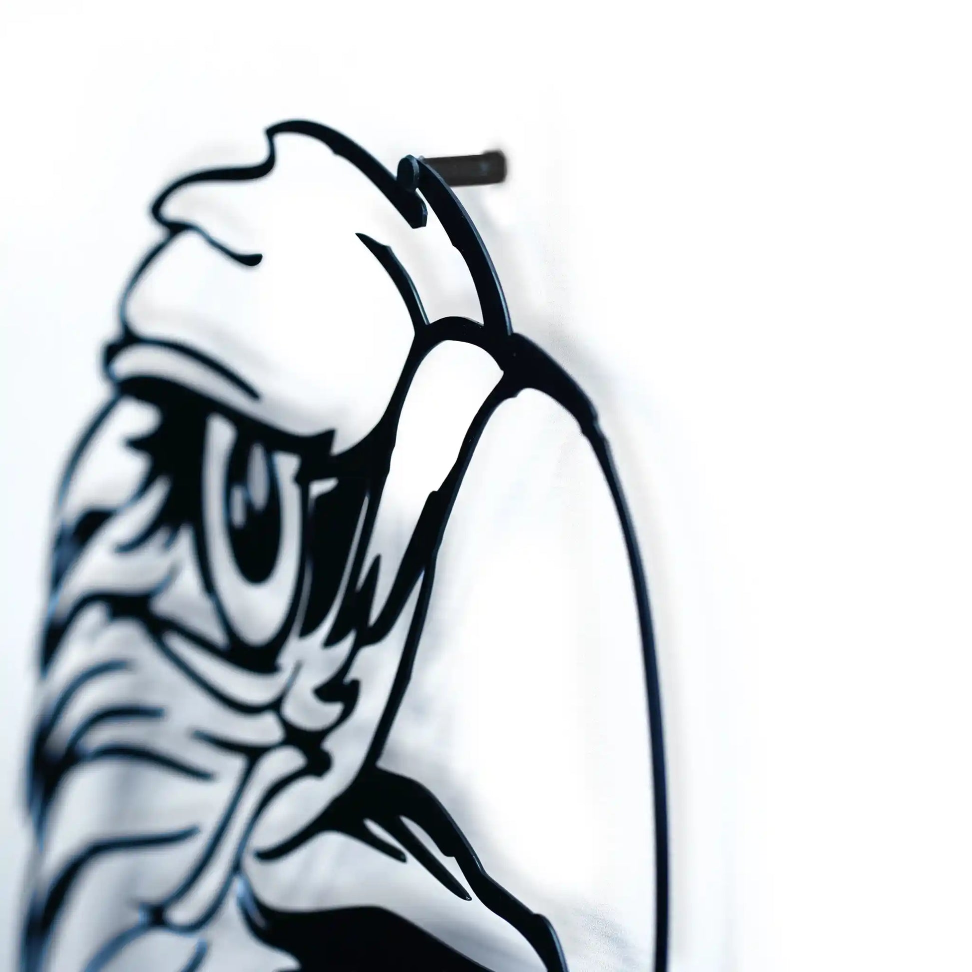 Black metal wall art of a stylized face of eagle on a white wall showing the shud