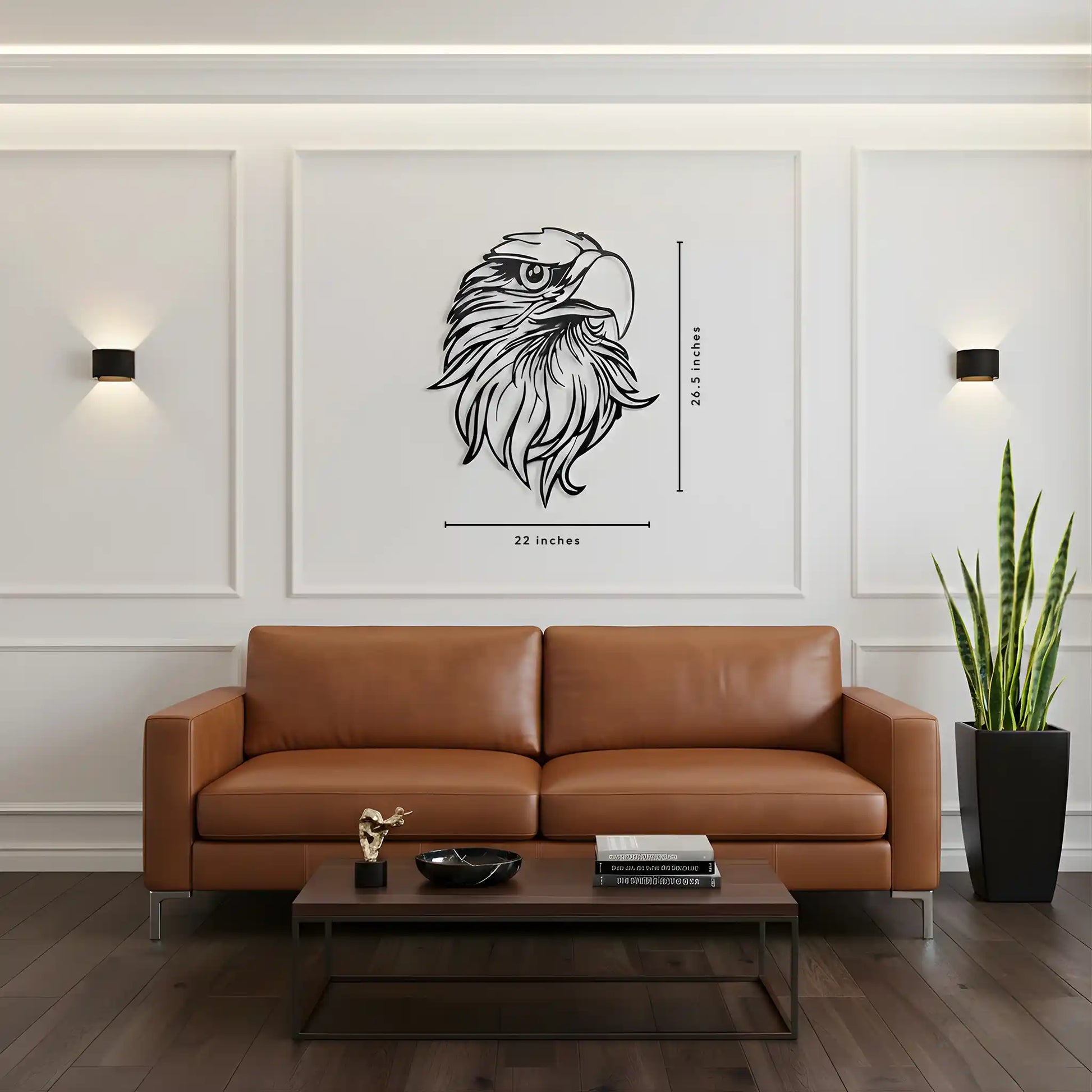 A framed black metal wall art of an eagle head with dimension markings (26.5 inches tall by 22 inches wide) displayed on a white wall above a brown leather sofa in a modern living room setting.