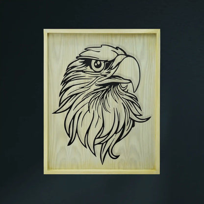 A diar wooden framed piece of metal wall art featuring a black line-art illustration of an eagle's head on a light natural wood background, shown against a dark charcoal wall.