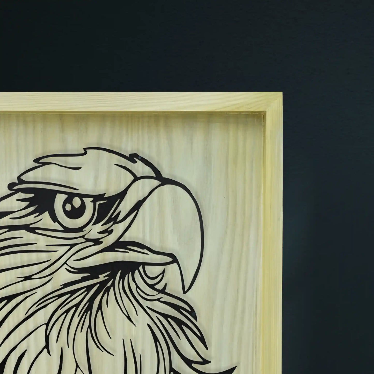 Wooden frame and metal wall art with an engraved eagle design on a dark background