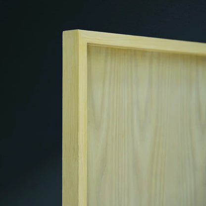 Close-up of a light natural wood framed board corner against a dark charcoal background.