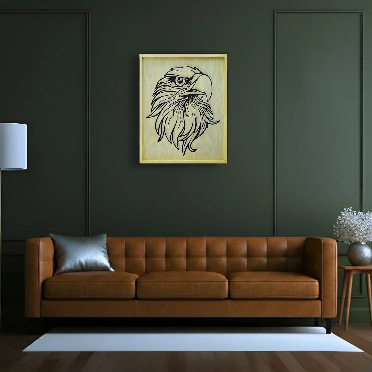 Living room with a brown leather sofa, a lamp, and a framed metal wall artwork of an eagle on a dark green wall.