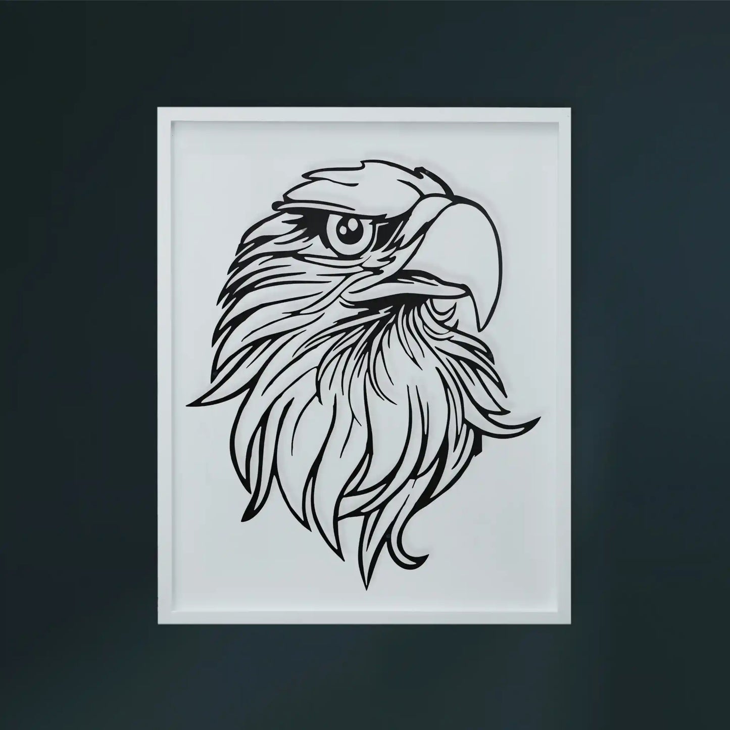 A framed black metal wall art of an eagle's head on a white wooden frame, displayed against a dark gray wall.