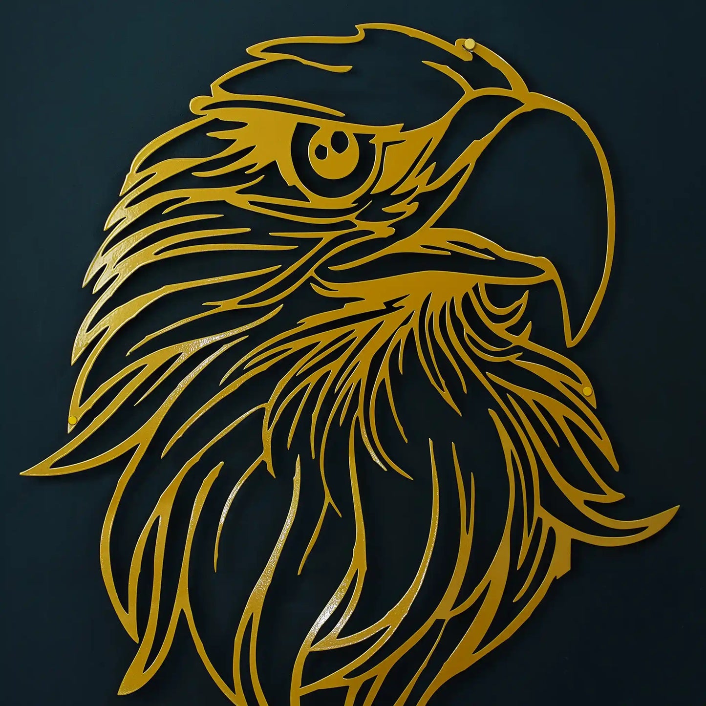 Gold metal wall art depicting an eagle head in profile, shown against a dark navy background.