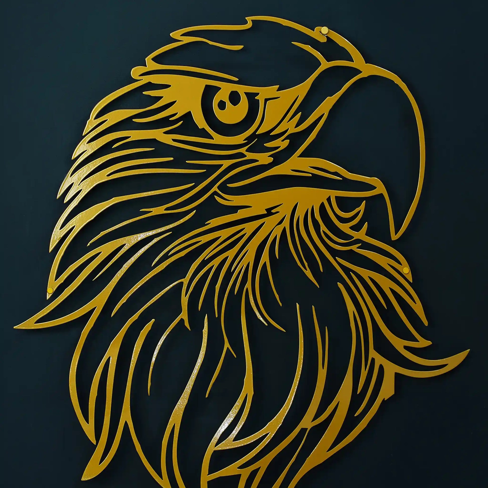 Gold metal wall art depicting an eagle head in profile, shown against a dark navy background.