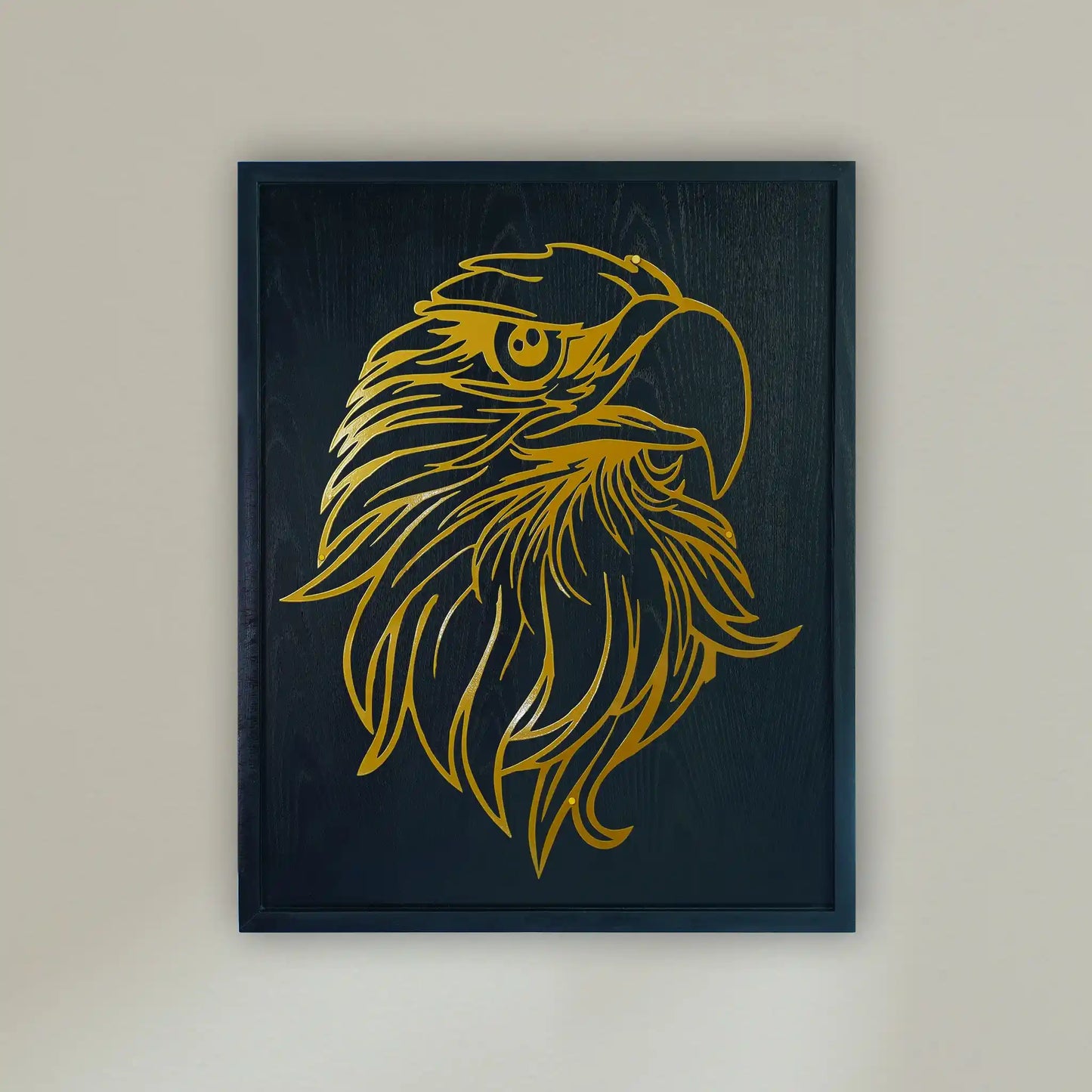 wooden Framed metal wall art featuring a stylized golden eagle head on a black wooden frame, hung on a light beige wall.