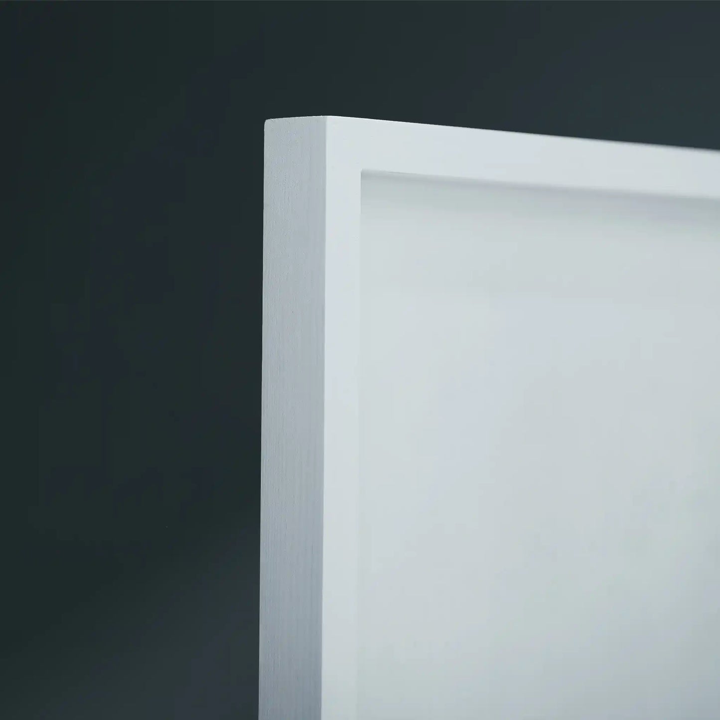 Close-up of a white wooden frame corner against a dark gray background.