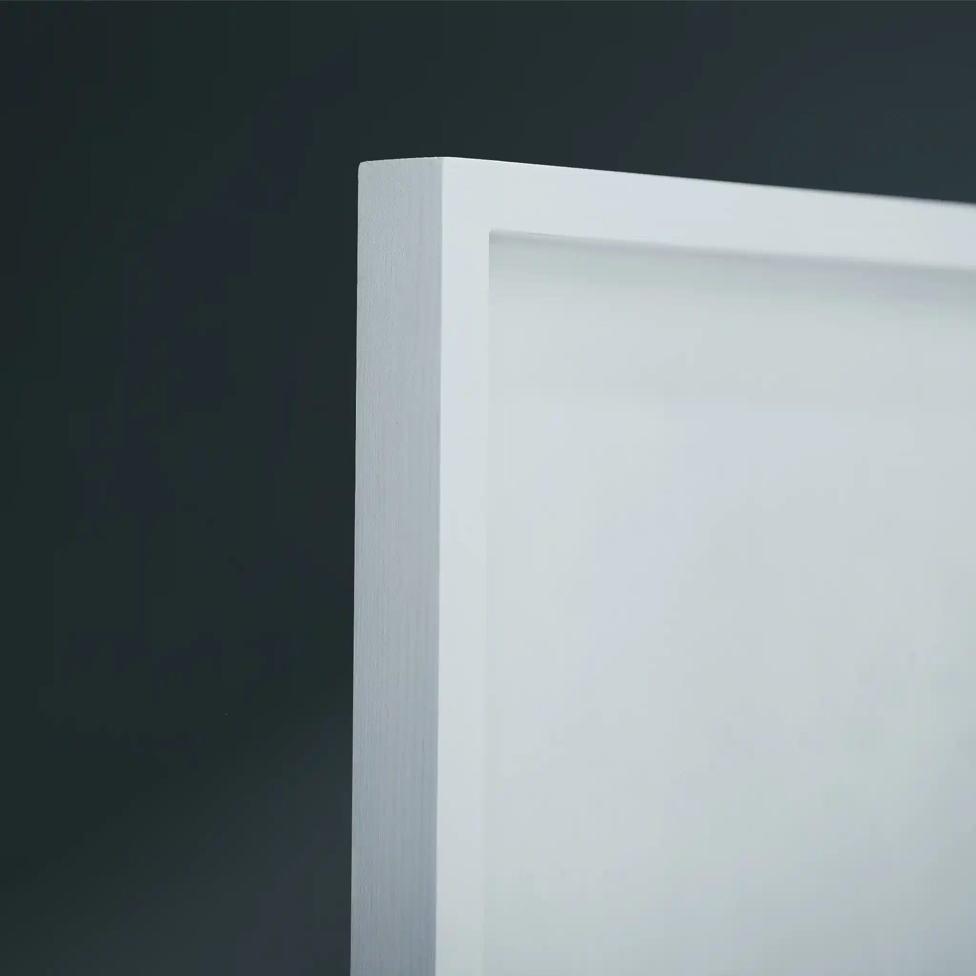 Close-up of a white wooden frame corner against a dark gray background.