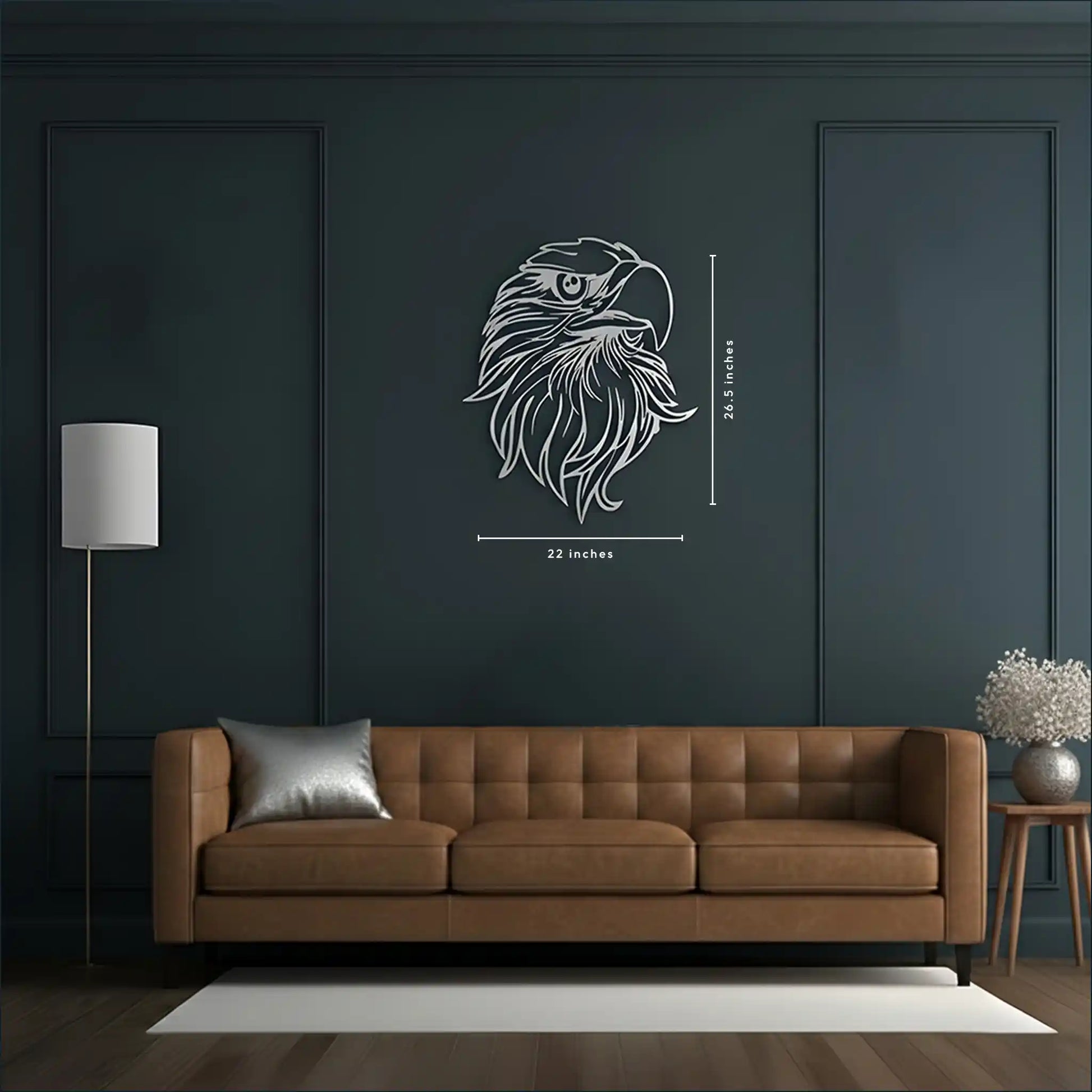 A brown tufted leather sofa in a modern living room, with a dark charcoal wall behind it featuring a metal wall art silver eagle head wall decal with dimension markings (22 inches wide by 26.5 inches tall).