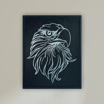 Framed wall art featuring a stylized metallic silver eagle head illustration on a black wood frame, hung on a light beige wall.