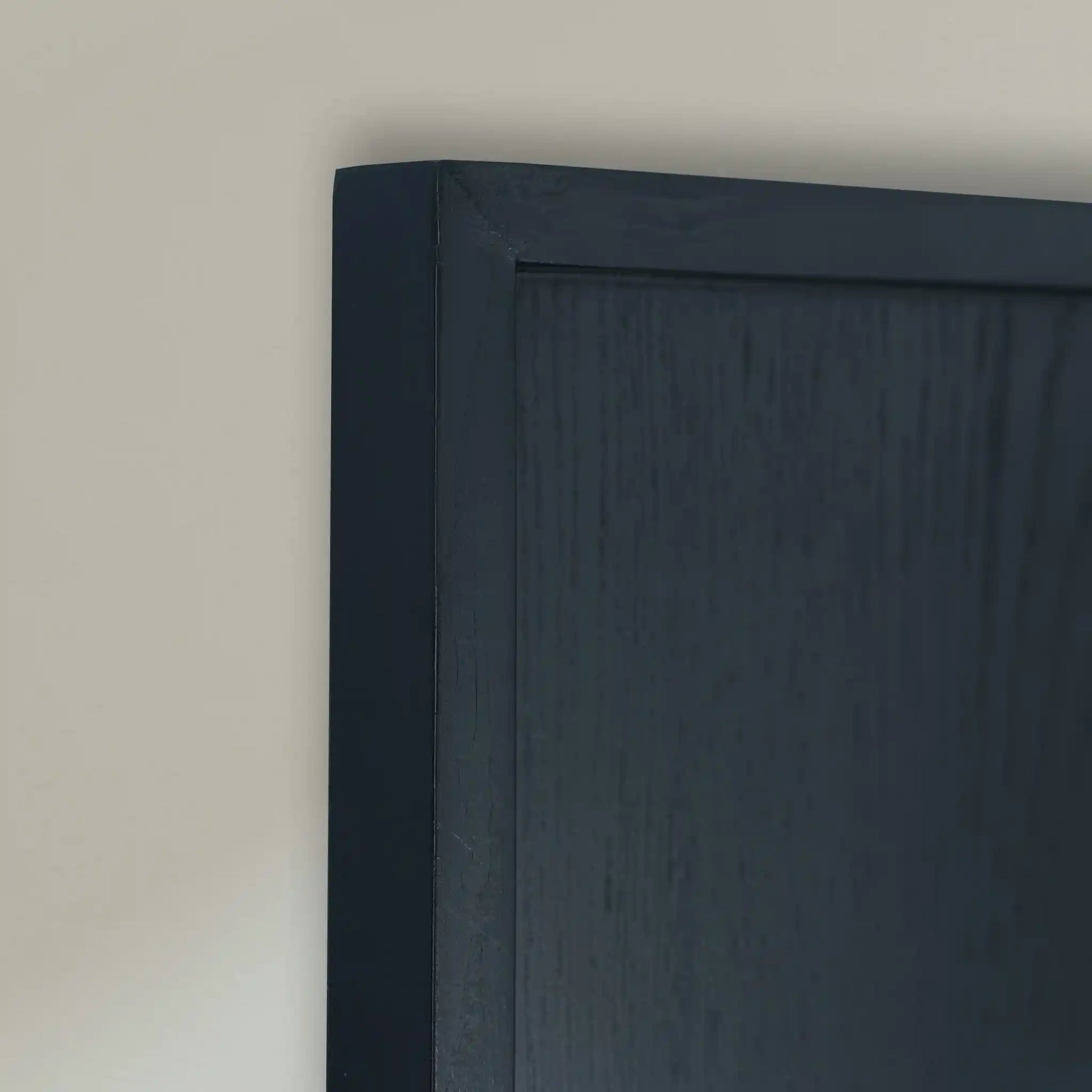 Close-up of black wooden frame corner on a beige wall