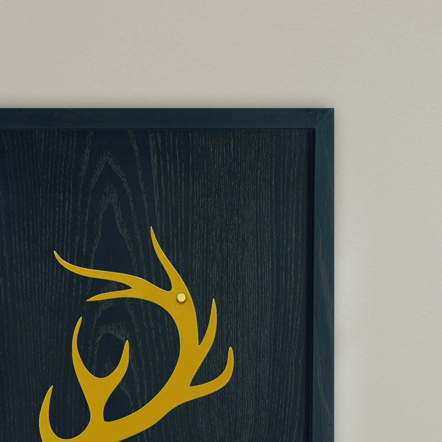 Framed artwork with a gold deer antler design on a black wooden frame with beige background