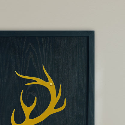 Framed artwork with a gold deer antler design on a black wooden frame with beige background