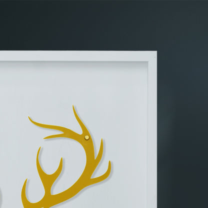 Gold deer antlers on a white wooden frame close shoot with a dark gray wall