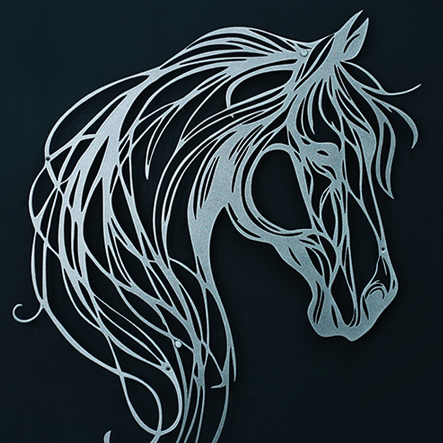 Decorative metal horse head sculpture on a black background