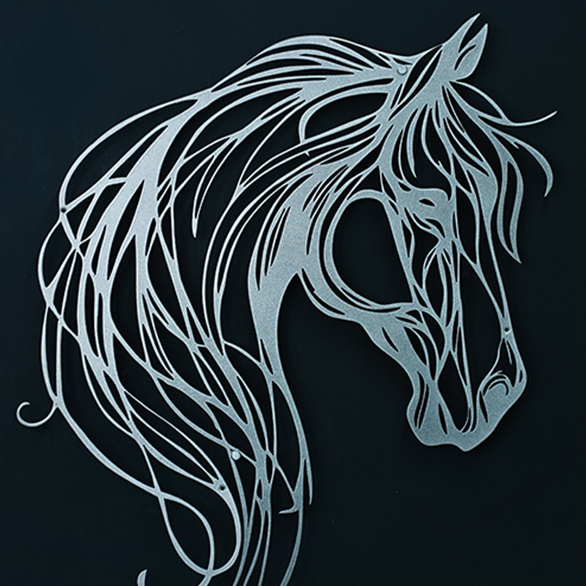 Decorative metal horse head sculpture on a black background