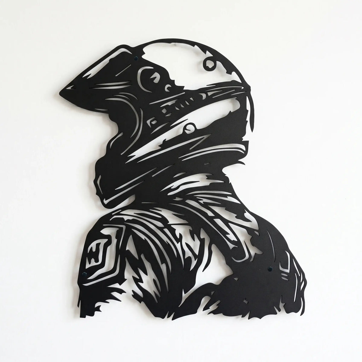 Black metal wall art depicting a motocross racer in a full-face helmet, shown against a plain white wall in  background.