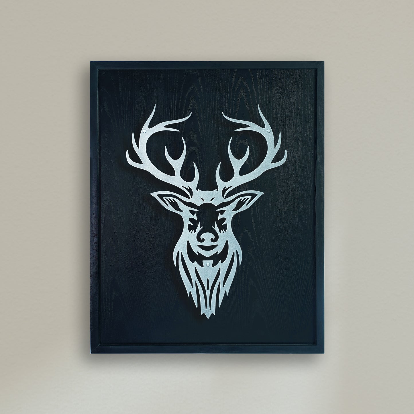 Black wooden Framed artwork of a deer head with antlers on a beige wall