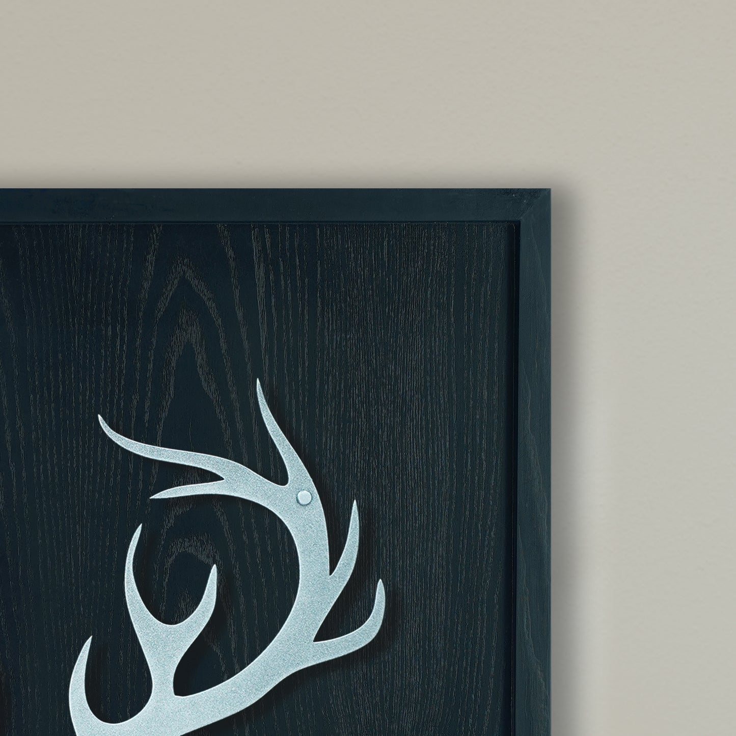 Decorative antler design on a dark wooden panel with a black frame.