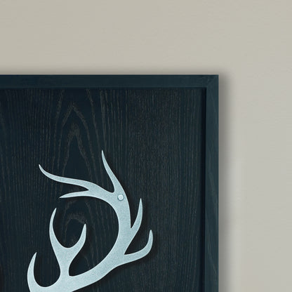 Decorative antler design on a dark wooden panel with a black frame.