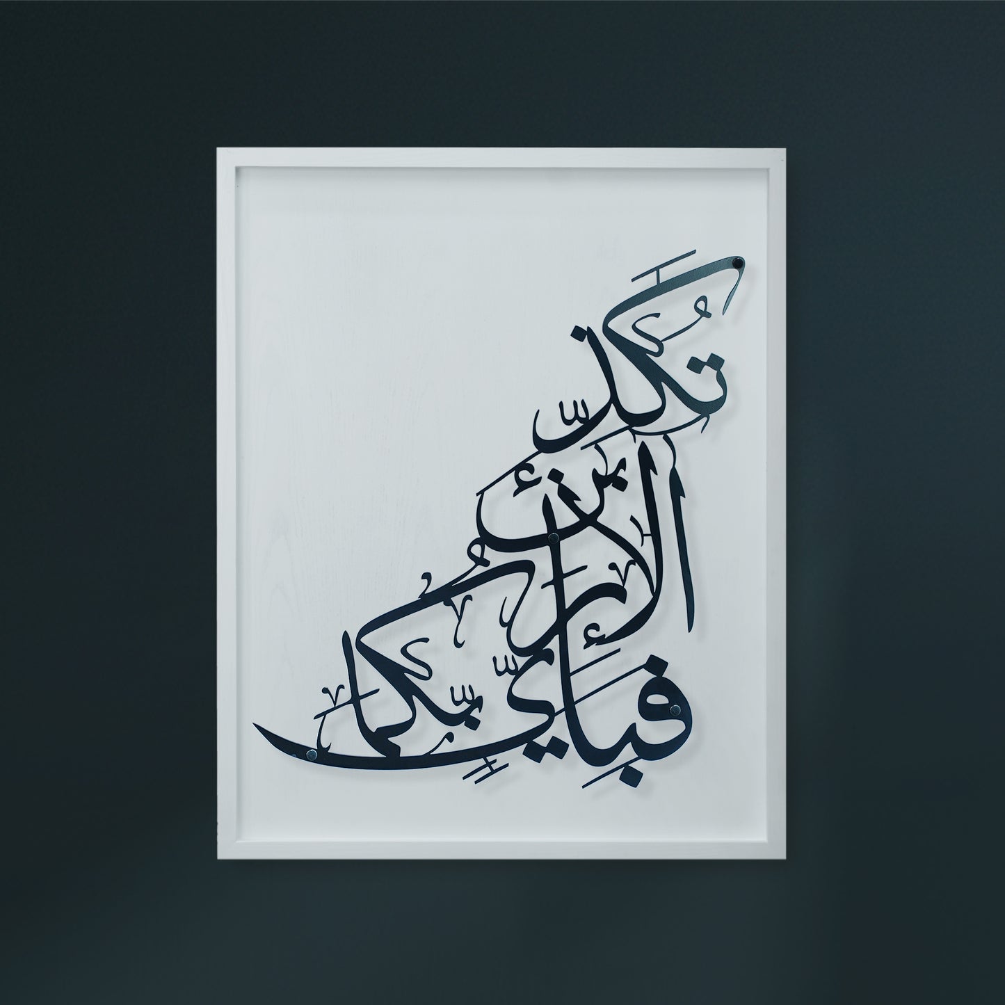 A framed Arabic calligraphy metal wall art  featuring black script on a white wooden, displayed against a dark charcoal wall.