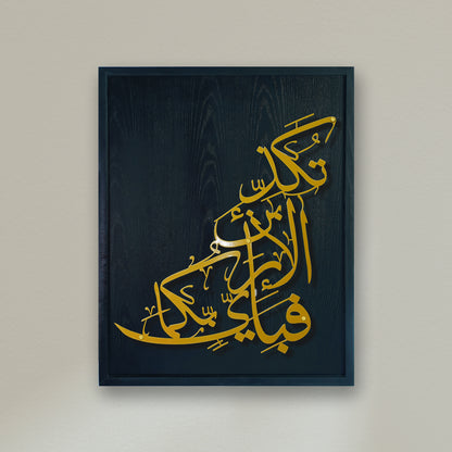 A framed Islamic metal wall art print featuring elegant gold Arabic calligraphy on a dark navy blue wood-grain textured background, mounted on a light beige wall.