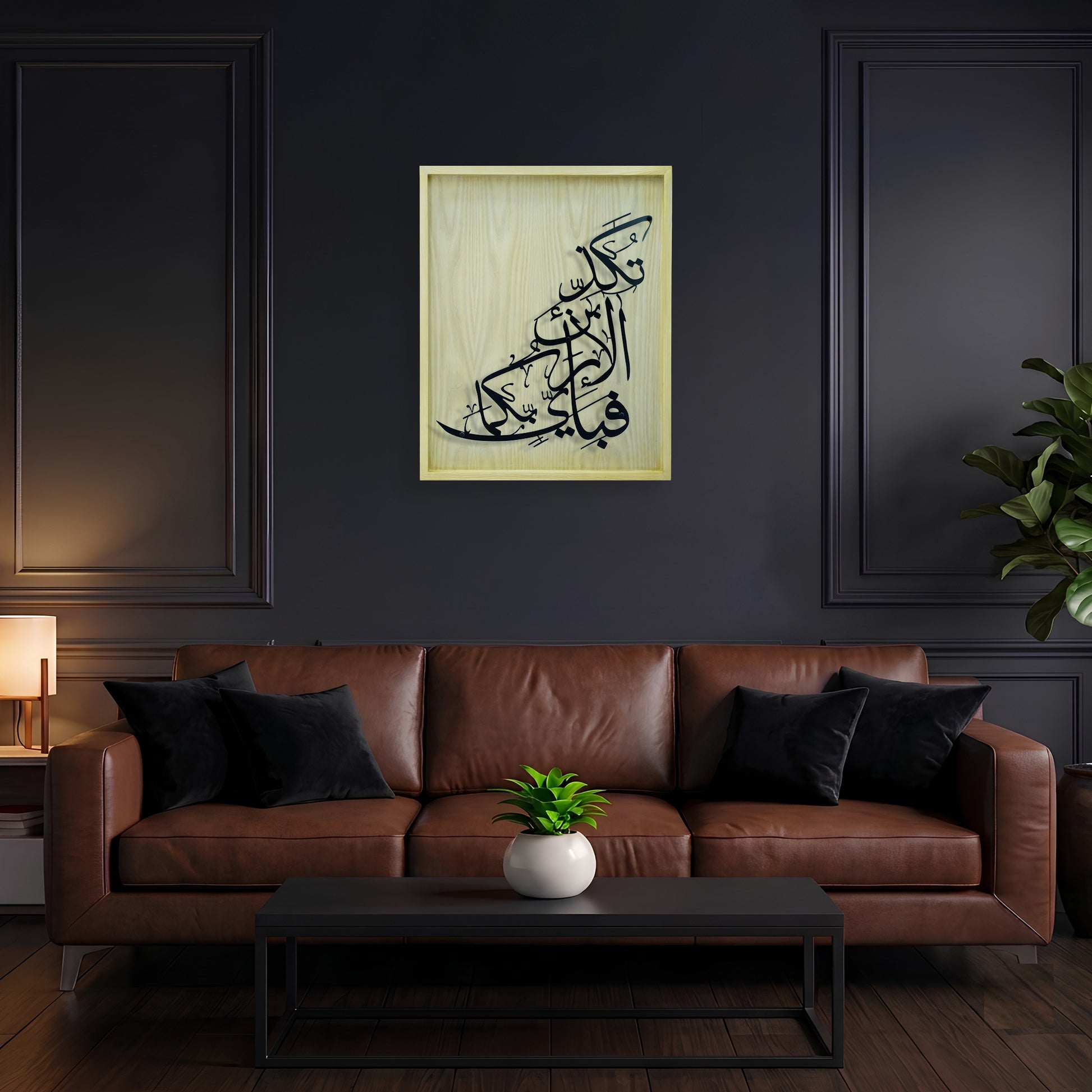 Framed Arabic calligraphy metal wall art in wooden frame hanging above a brown leather sofa in a dark modern living room.