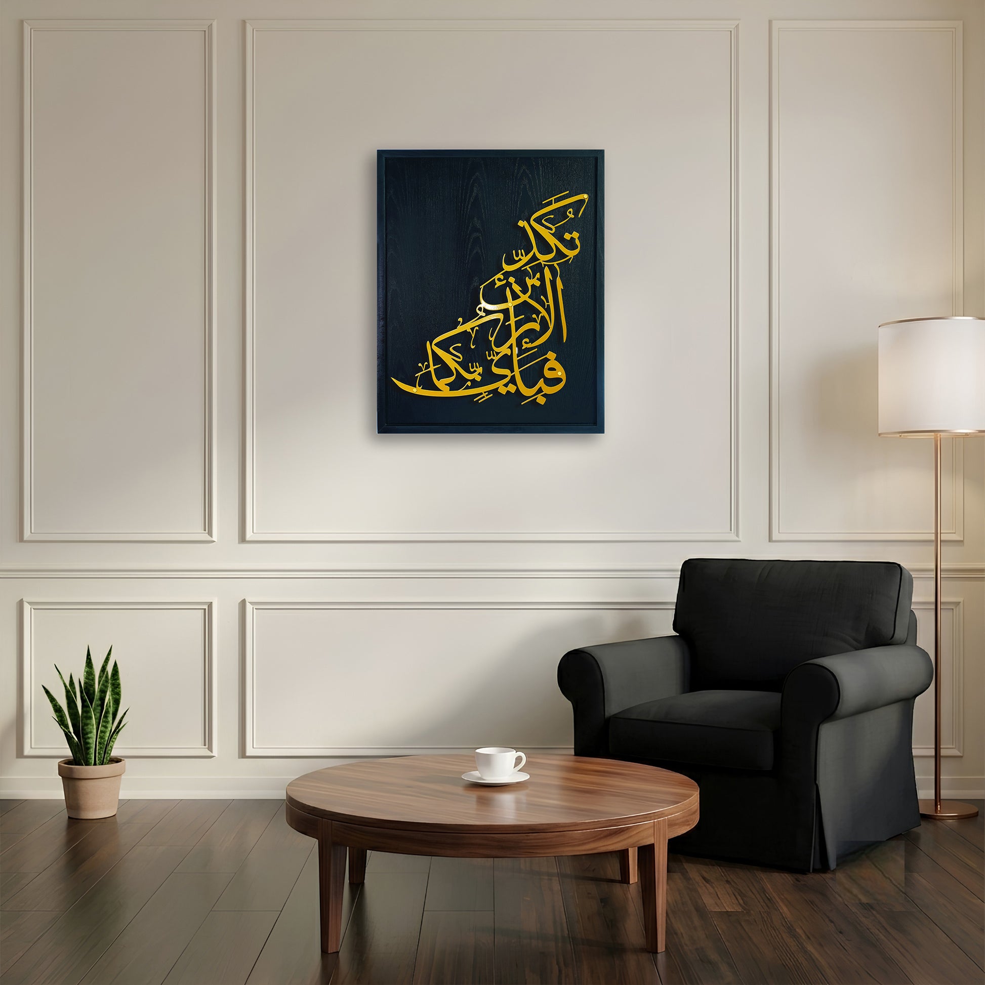A wooden framed Islamic calligraphy metal wall art in golden Arabic script on a black wooden frame, displayed in a modern living room setting above a round wooden coffee table and next to a black armchair.