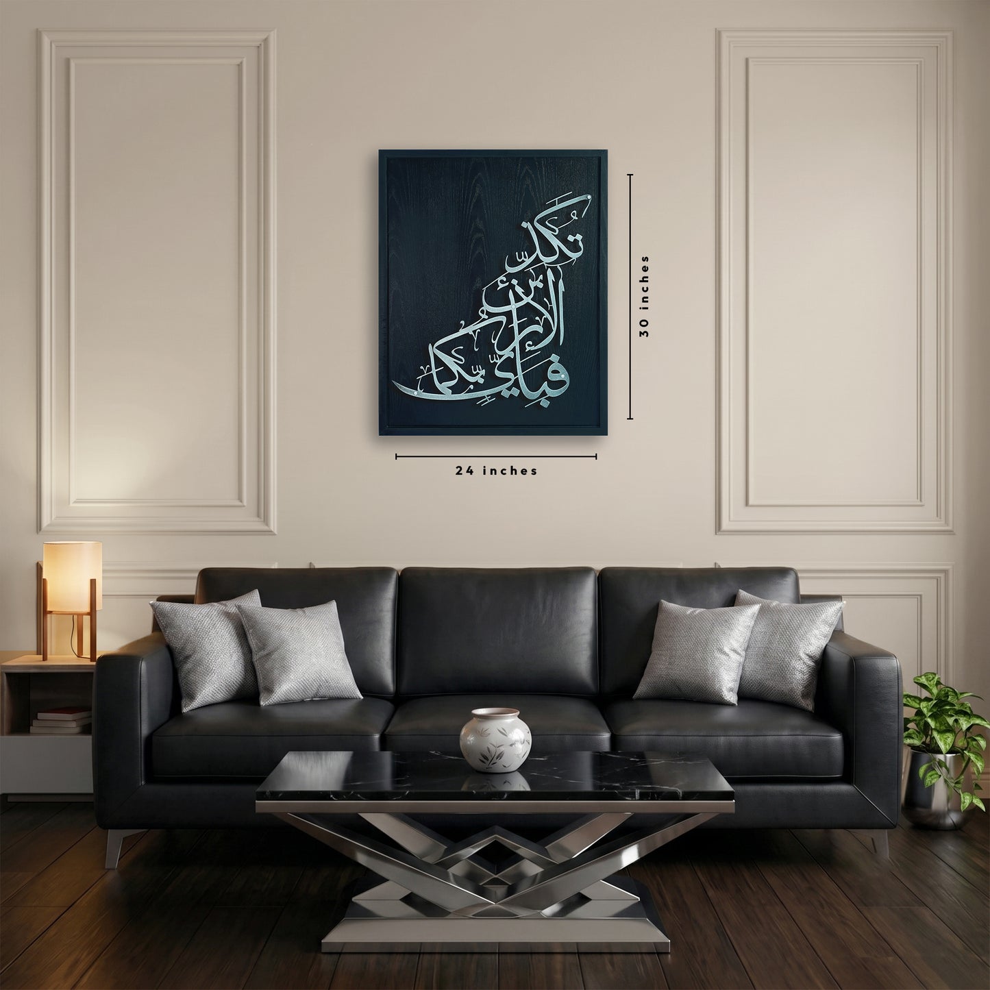 A framed wooden metal wall art silver Arabic calligraphy on a black wooden frame, shown hanging above a black leather sofa in a styled living room. Measurement labels indicate 24 inches wide by 30 inches tall.
