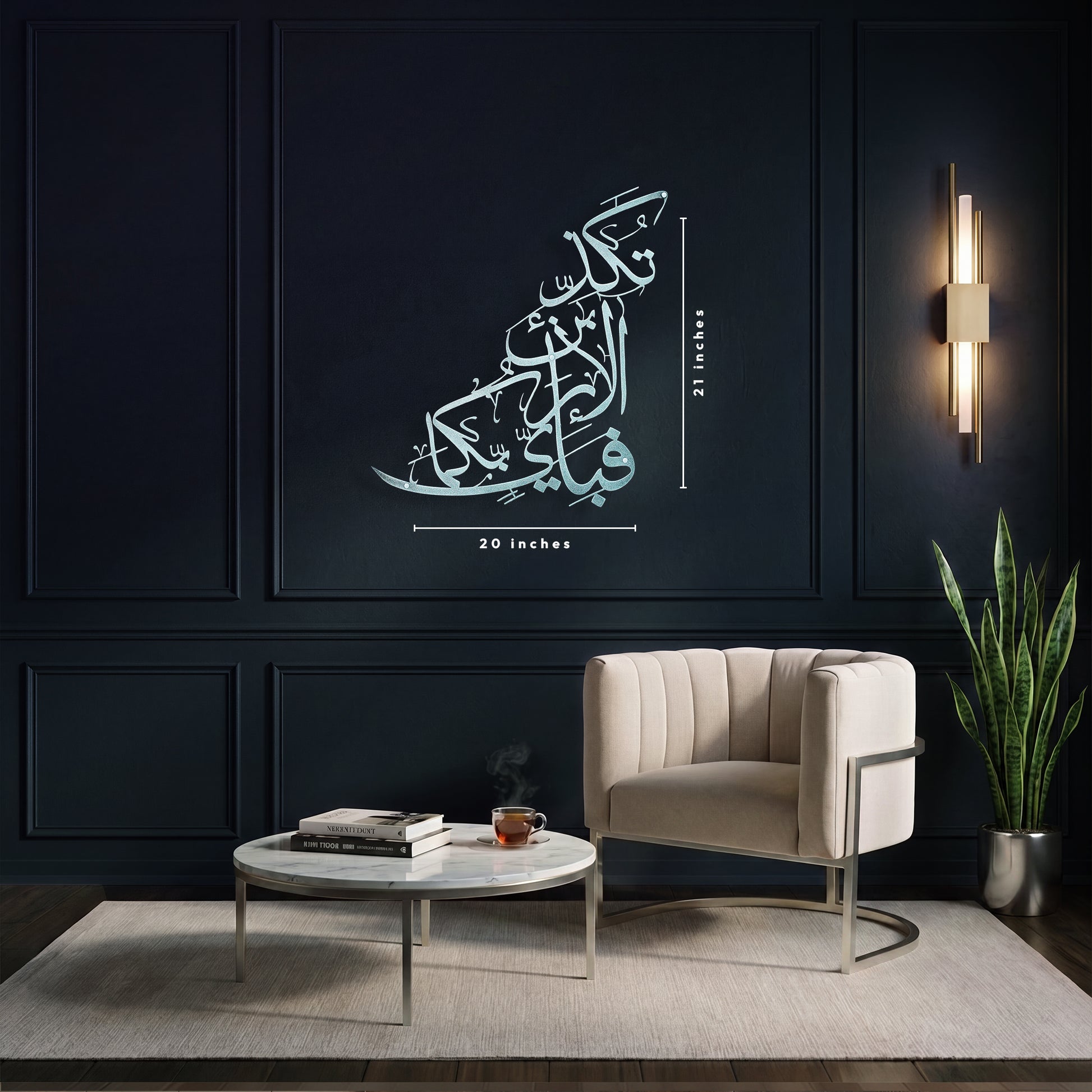 A large Arabic calligraphy metal wall art displayed in a modern living room setting. The silver islamic calligraphy features in a stylized, layered font with dimension lines indicating it is 20 inches wide and 21 inches tall.