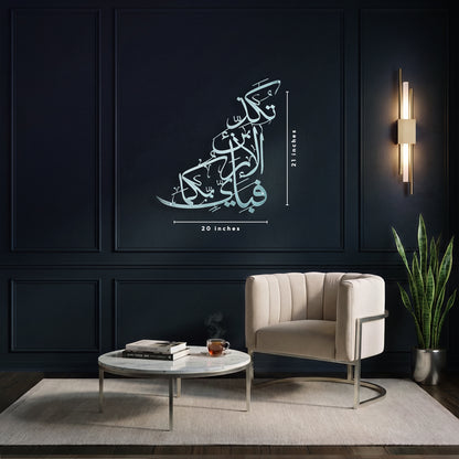 A large Arabic calligraphy metal wall art displayed in a modern living room setting. The silver islamic calligraphy features in a stylized, layered font with dimension lines indicating it is 20 inches wide and 21 inches tall.