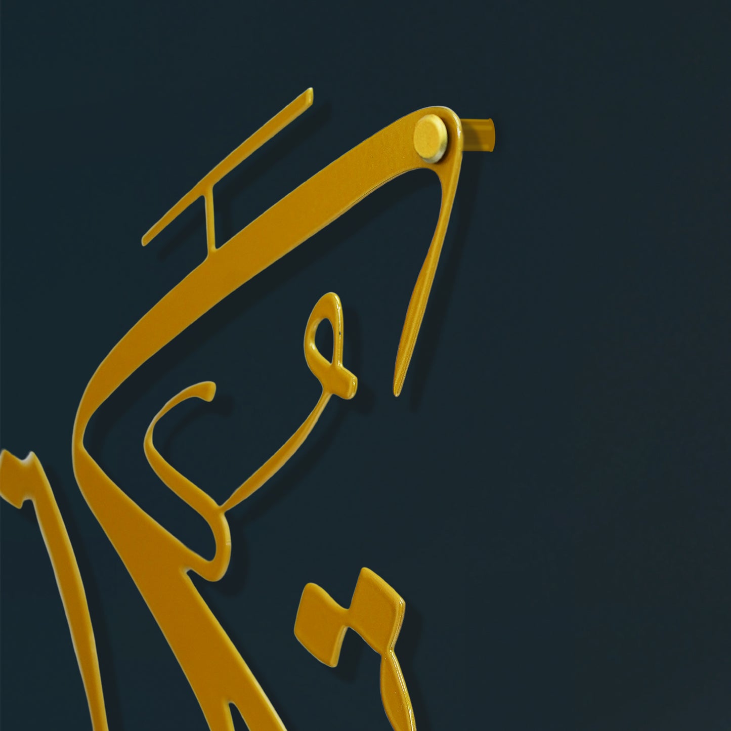 A close-up of a glossy gold Arabic calligraphy design on a dark navy blue background.