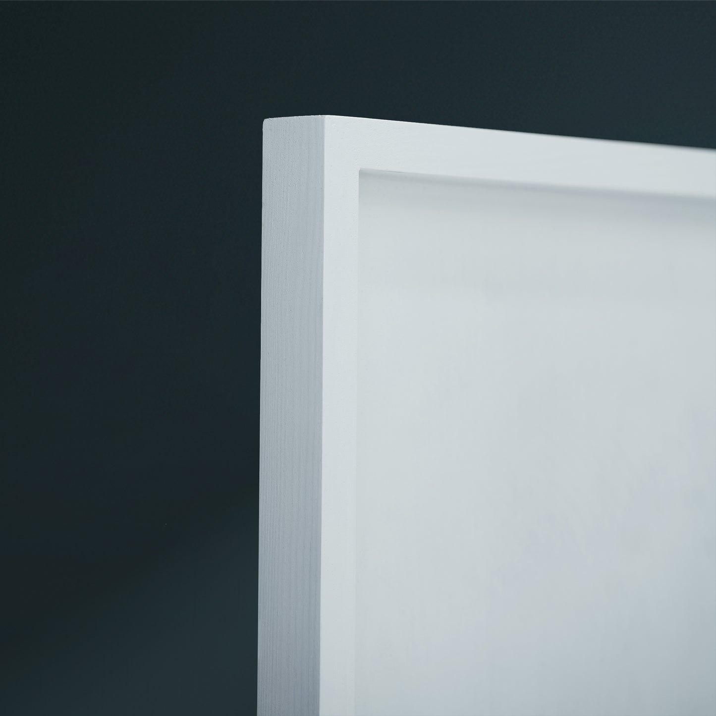 Close-up of a white frame corner against a dark charcoal background.