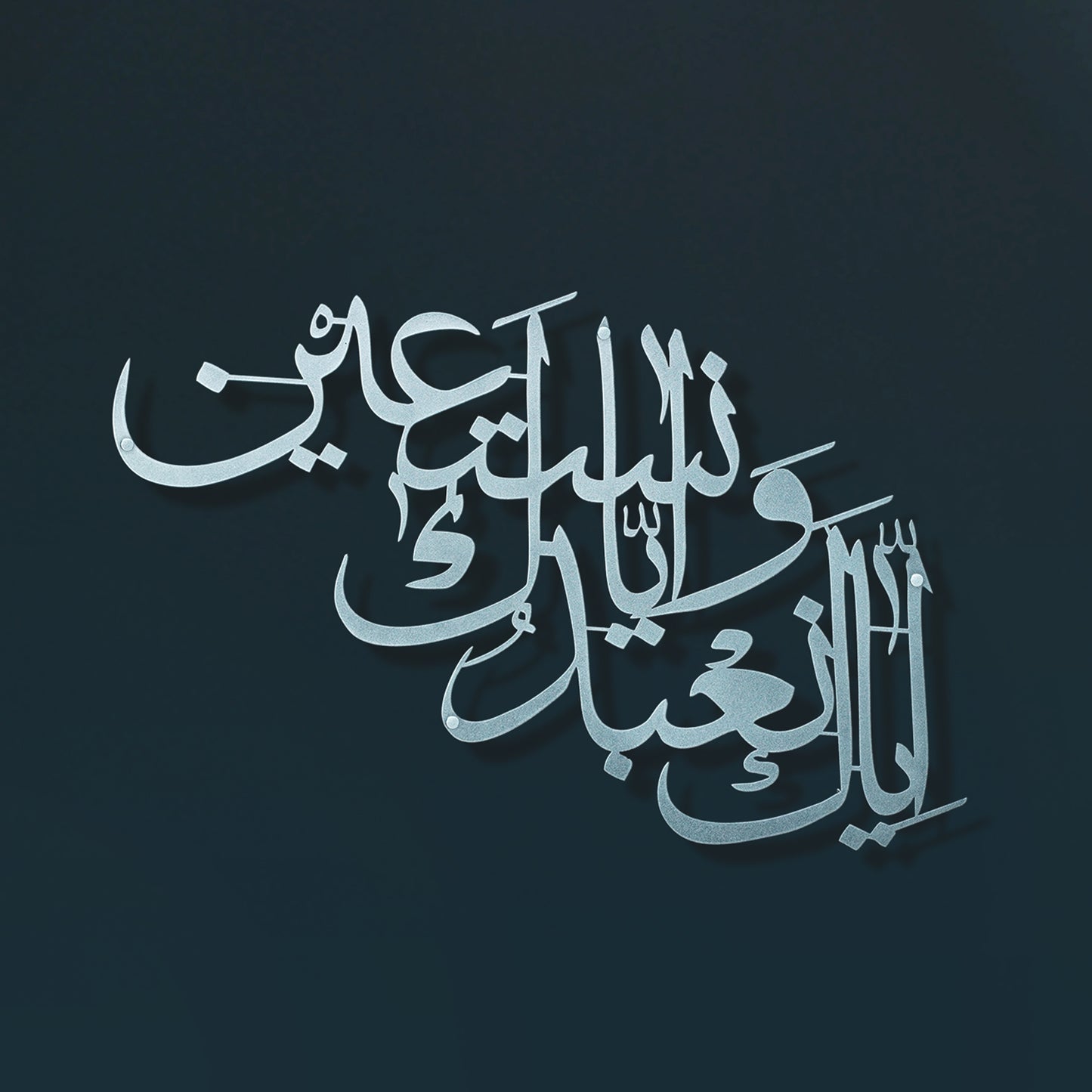 Arabic calligraphy metal wall art in a metallic silver tone on a dark teal background.