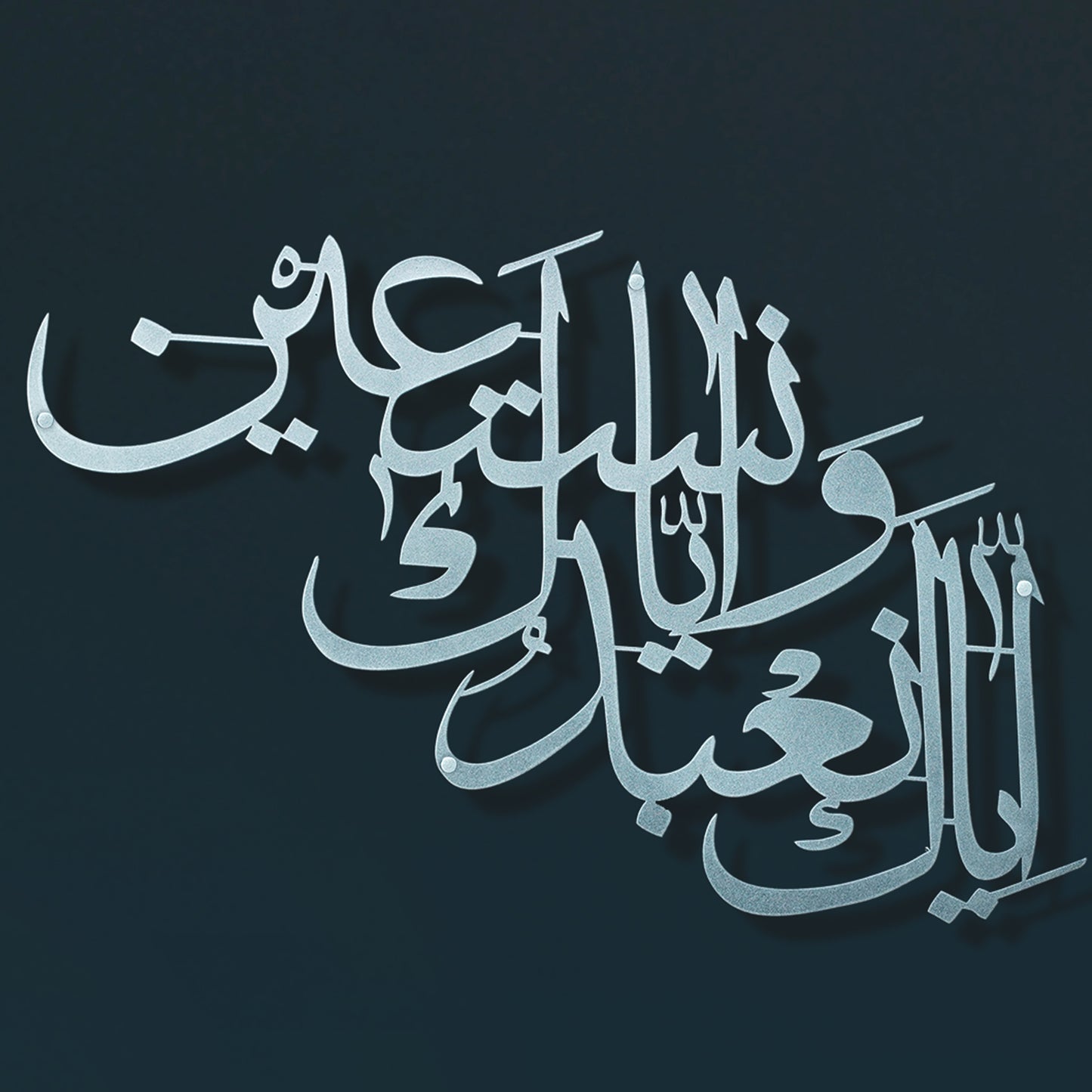 Silver Arabic calligraphy metal wall art shown against a dark navy blue background.