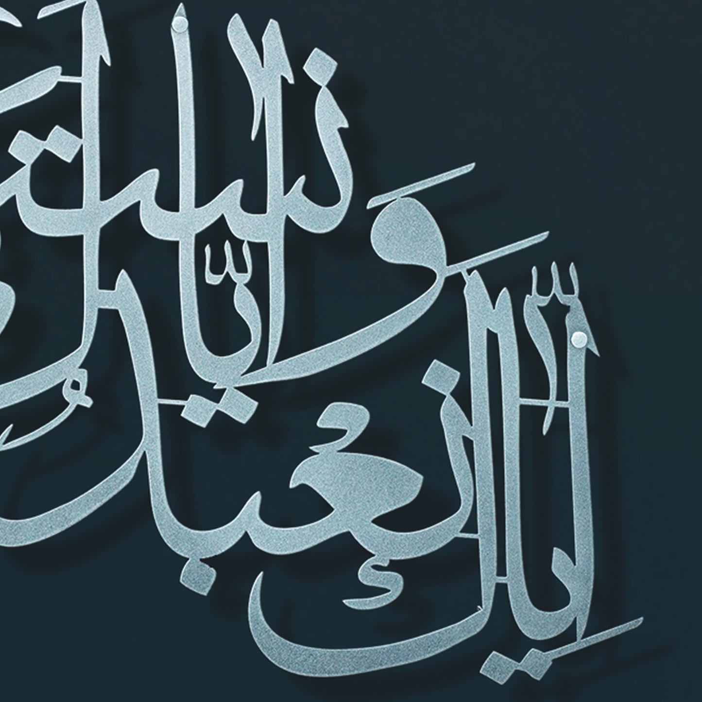 Silver Arabic calligraphy metal wall art on a dark navy background.