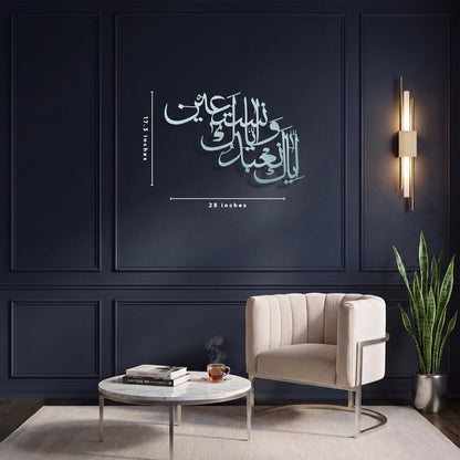 A styled interior room with dark navy paneled walls, a beige armchair, a round white coffee table, and a potted snake plant. The focal product appears to be the metal wall art: silver Arabic calligraphy with small dimension markings reading 28 inches width and 17.3 inches tall