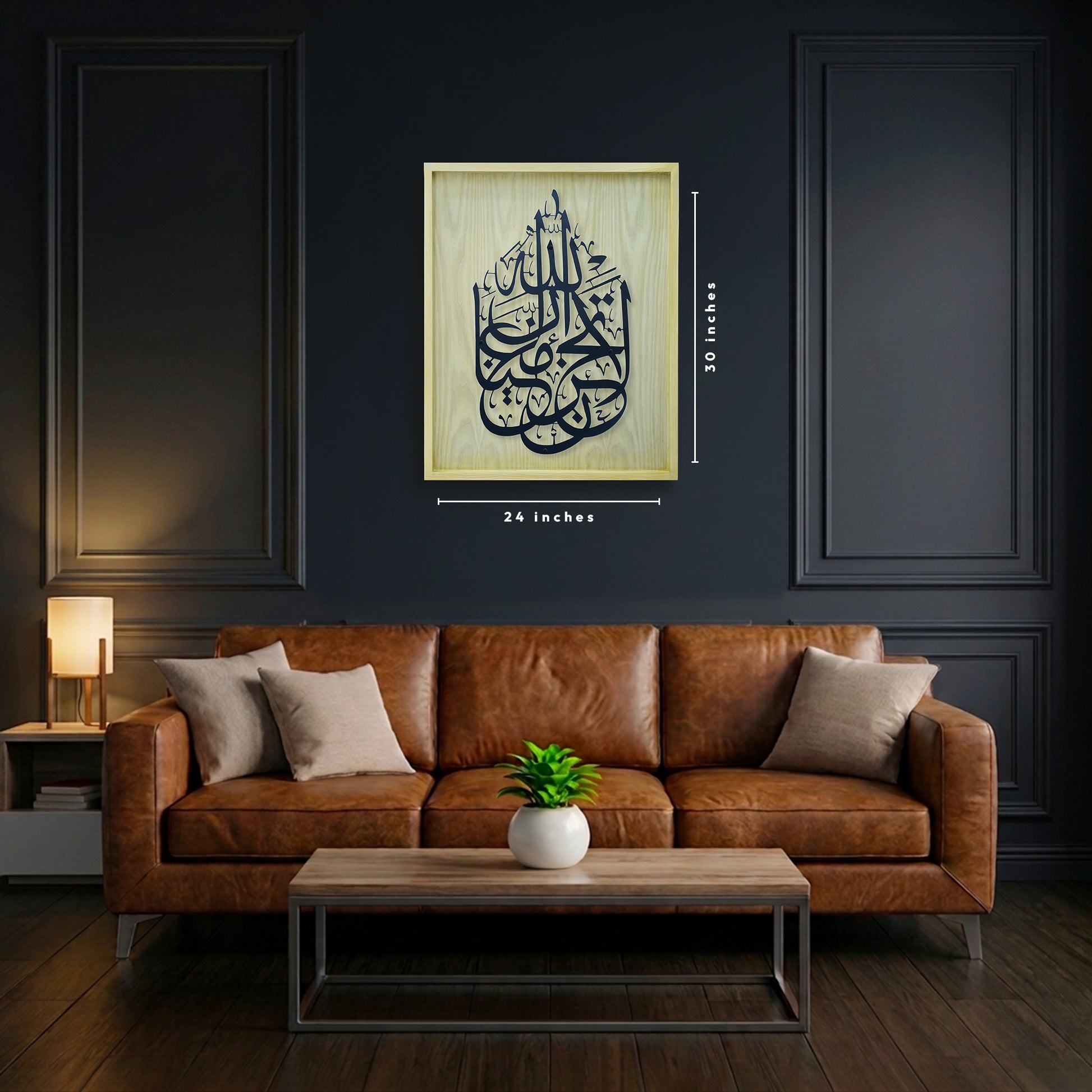 A framed Arabic calligraphy wall art CNC laser Cut hangs above a brown leather sofa in a dark living room. The art has a wood frame with black calligraphy.