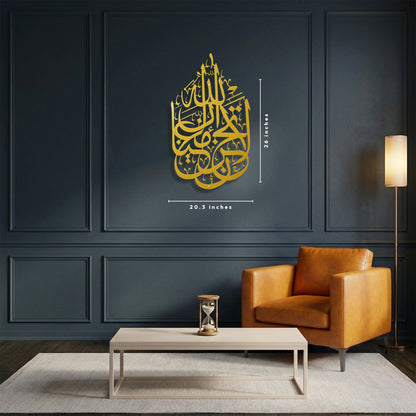 Gold calligraphy La Tahzan İnnallahe Maana, Metal Wall Art inside a house silhouette, shown in a modern living room setting on a dark paneled wall with a brown leather armchair and a coffee table. The image includes dimension lines indicating the frame is length 26 inches and width 20.3 inches.