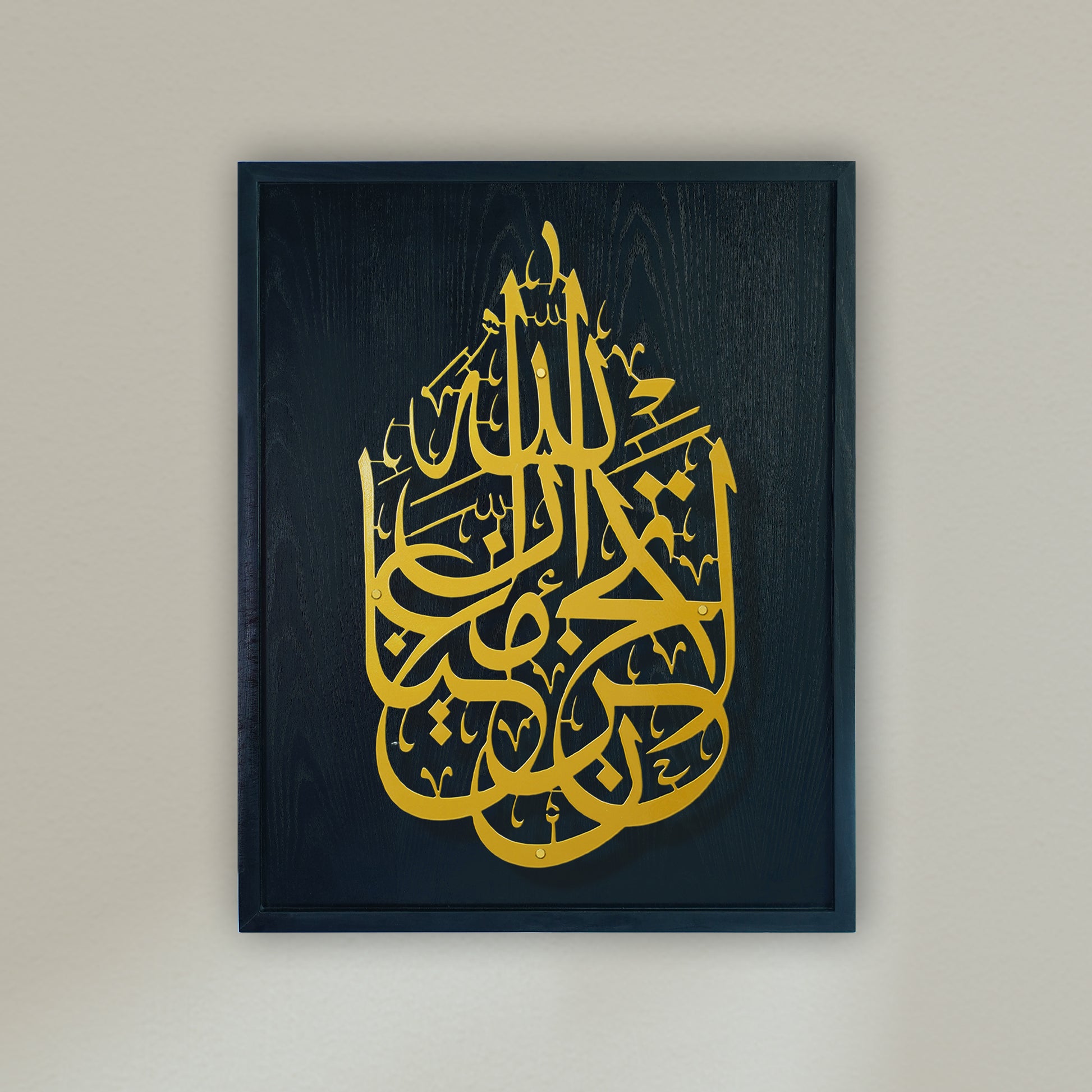Framed Islamic wall art featuring intricate gold Arabic calligraphy on a blue wooden frame, mounted on a light beige wall.