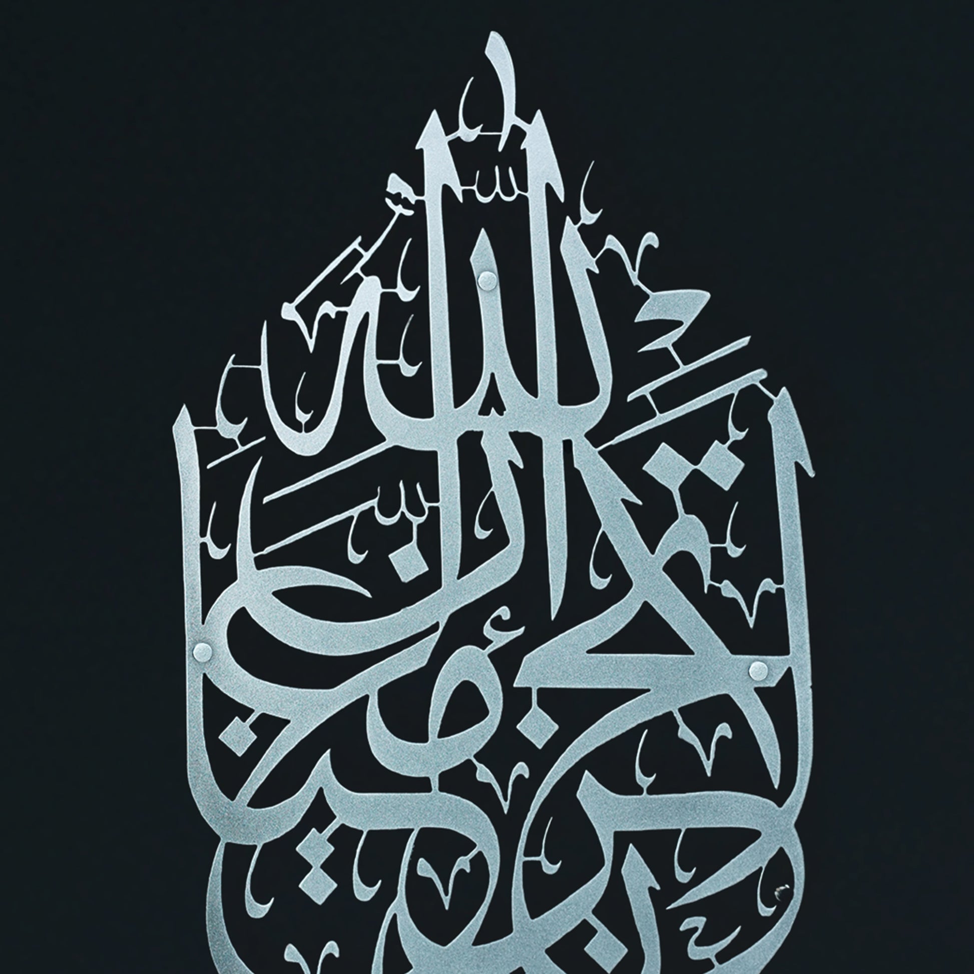 Silver La Tahzan İnnallahe Maana, Islamic  calligraphy Metal Wall Art in an ornate, layered geometric design, displayed against a solid black background.